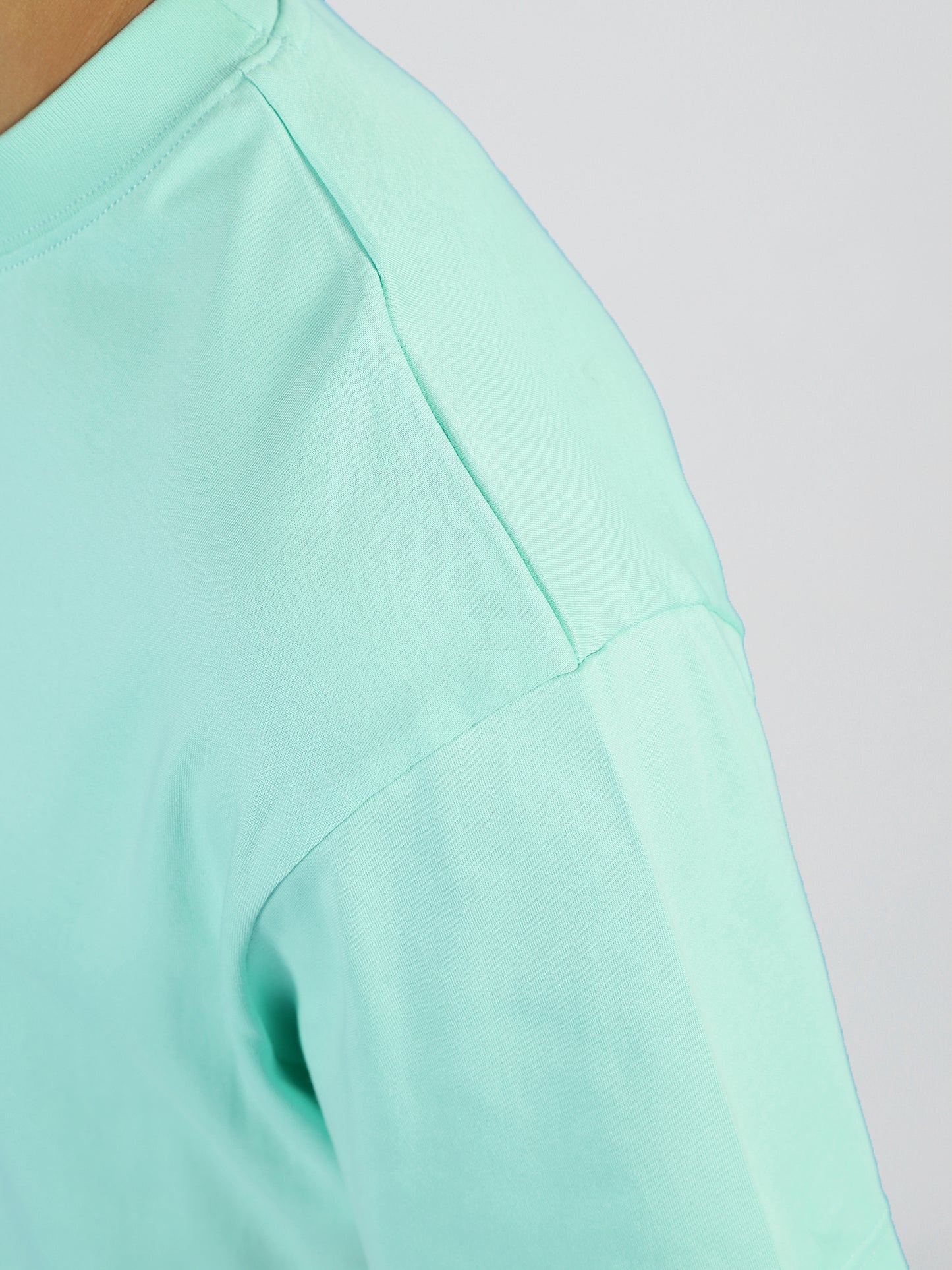 Close-up of the shoulder and upper sleeve of a person wearing the Vibe T- Cabbage- Men by My Store, showing the fabric texture and seam details of this premium cotton blend against a plain light background.