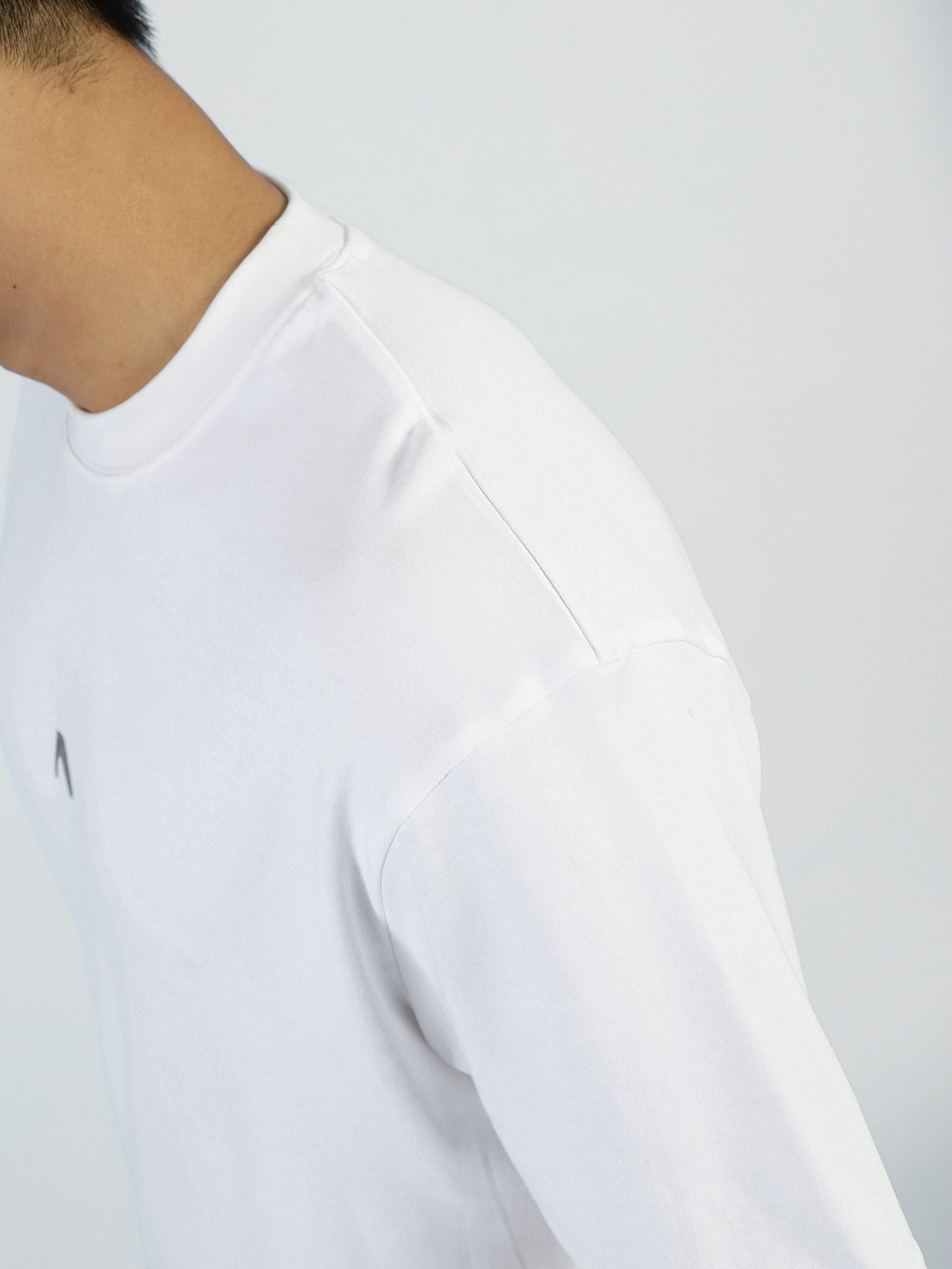 A man wears the My Store Vibe T in Bright White, made from a premium cotton blend. Shown from neck to upper arm and facing slightly away, only part of his face and body are visible against a light background.