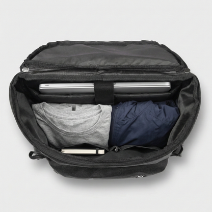 Black backpack with clothes and a laptop inside on a light gray background